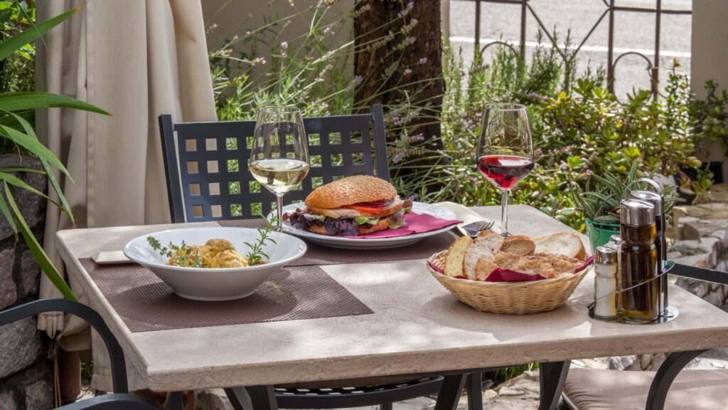 Outdoor restaurant table with food, bread, and wine glasses